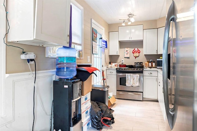 kitchen with light wood-type flooring, white cabinets, and appliances with stainless steel finishes