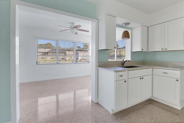 kitchen featuring pendant lighting, ceiling fan, sink, and white cabinets