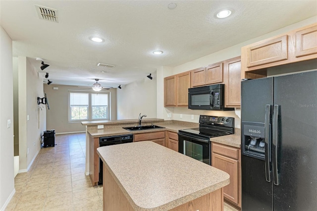 kitchen with kitchen peninsula, a center island, black appliances, and sink