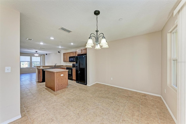 kitchen featuring a center island, kitchen peninsula, decorative light fixtures, black appliances, and ceiling fan with notable chandelier