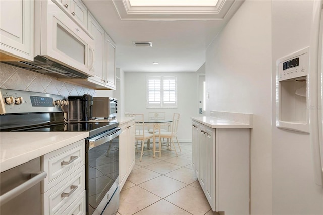 kitchen featuring tasteful backsplash, white cabinetry, light tile patterned flooring, and stainless steel appliances