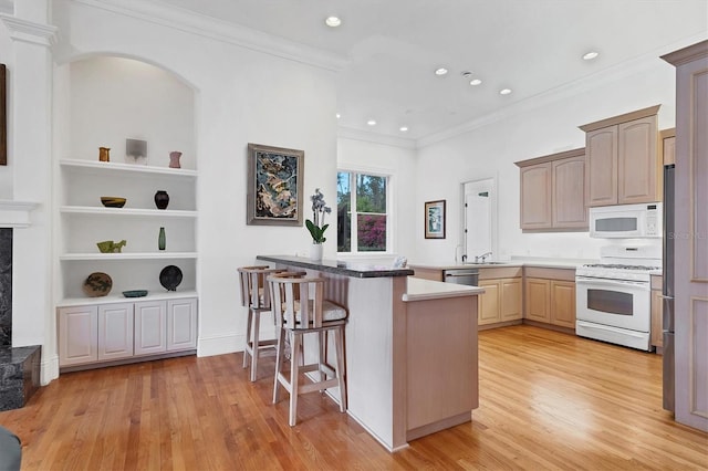 kitchen with appliances with stainless steel finishes, built in shelves, light brown cabinets, kitchen peninsula, and a breakfast bar