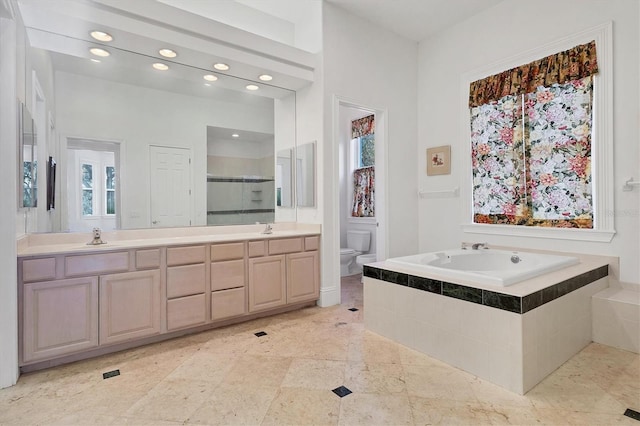 bathroom with toilet, tiled tub, and vanity