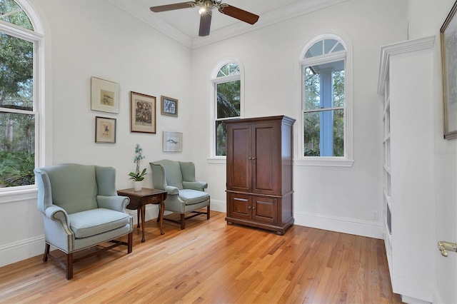 sitting room featuring light wood-type flooring, ceiling fan, and ornamental molding