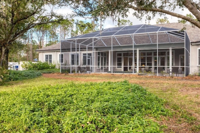 back of property with a lanai and a lawn