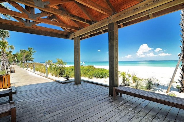 wooden deck with a water view and a view of the beach