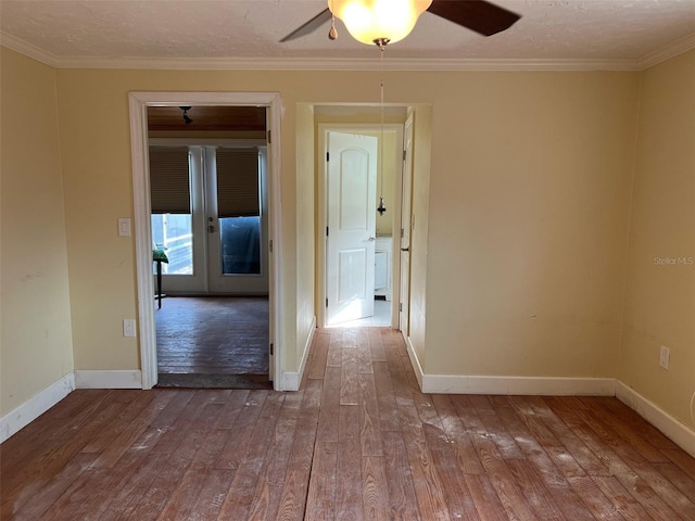 empty room featuring a textured ceiling, ceiling fan, crown molding, and wood-type flooring