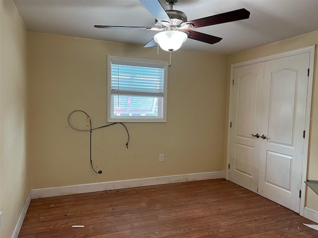 unfurnished bedroom with ceiling fan, wood-type flooring, and a closet