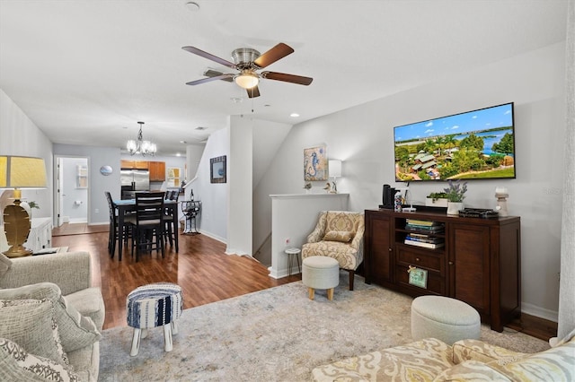 living room with ceiling fan with notable chandelier, wood-type flooring, and vaulted ceiling