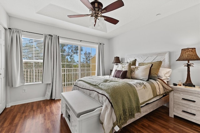 bedroom featuring ceiling fan, a raised ceiling, dark wood-type flooring, and access to outside