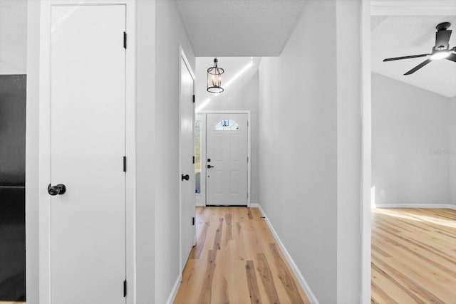 hallway with light hardwood / wood-style floors, lofted ceiling, and a textured ceiling