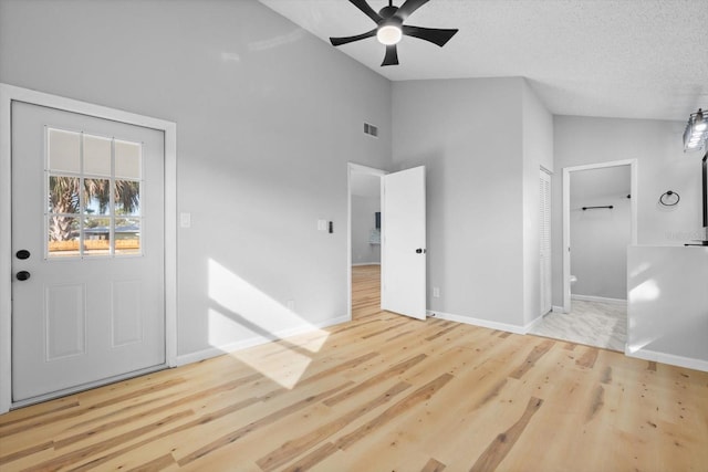 foyer entrance with ceiling fan, light hardwood / wood-style flooring, high vaulted ceiling, and a textured ceiling