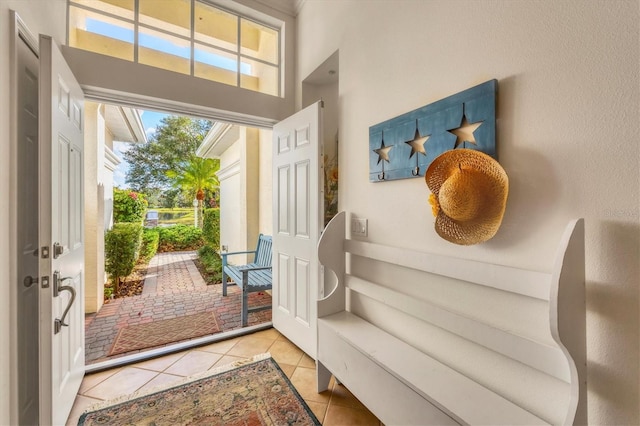 entryway with light tile patterned flooring and a towering ceiling