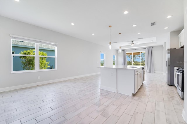 kitchen featuring stainless steel appliances, a kitchen island, ceiling fan, white cabinetry, and hanging light fixtures