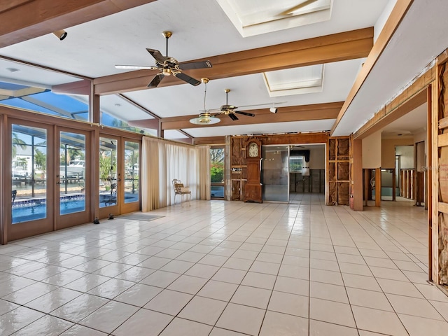 interior space featuring lofted ceiling with skylight, light tile patterned flooring, french doors, and ceiling fan