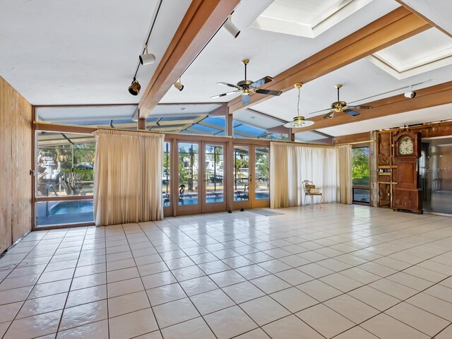 interior space with vaulted ceiling with beams, plenty of natural light, light tile patterned flooring, and wooden walls