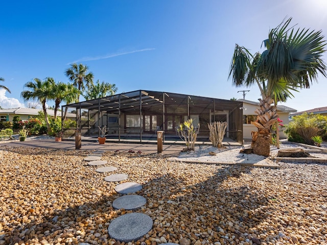 rear view of property featuring a patio, a pool, and glass enclosure