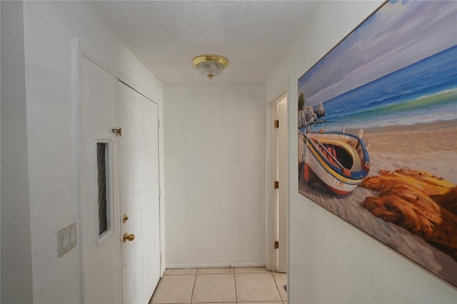 hall featuring a textured ceiling and light tile patterned flooring