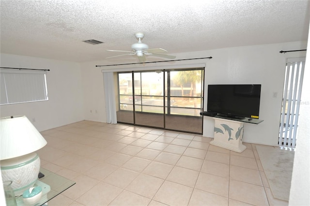 unfurnished living room featuring ceiling fan, light tile patterned floors, and a textured ceiling