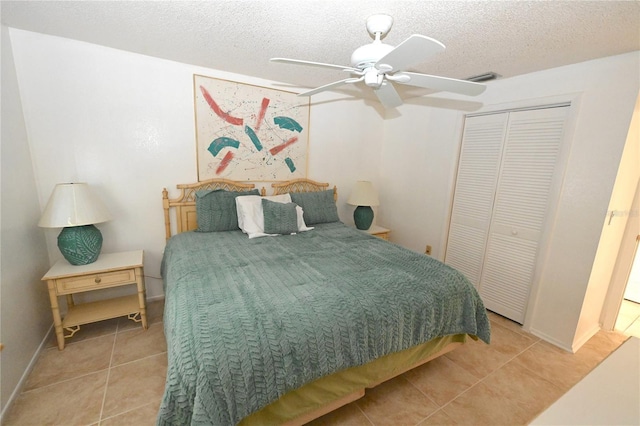 bedroom with a textured ceiling, a closet, tile patterned floors, and ceiling fan