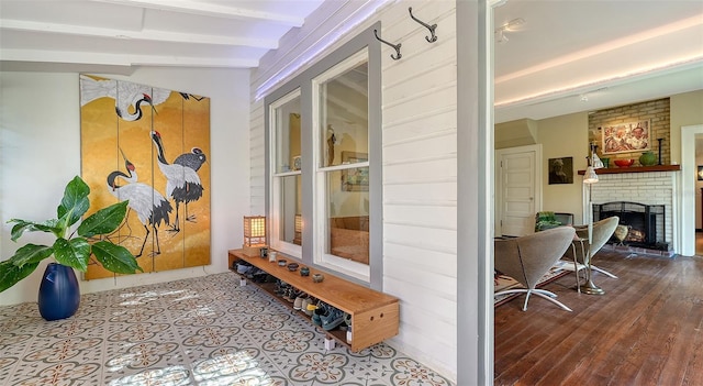 mudroom with lofted ceiling with beams and a brick fireplace