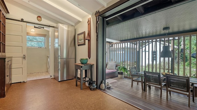 interior space with a barn door, lofted ceiling with beams, and washer / clothes dryer