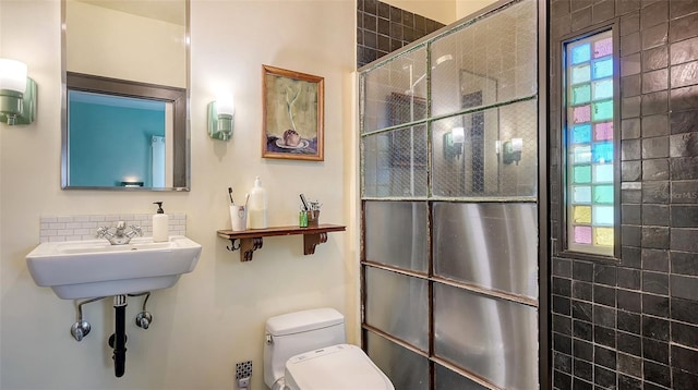 bathroom featuring toilet, tiled shower, a wealth of natural light, and tasteful backsplash