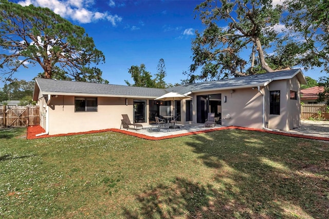 rear view of property with a lawn and a patio