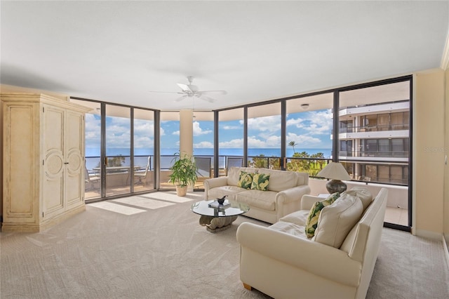 living room featuring ceiling fan, a water view, and light colored carpet