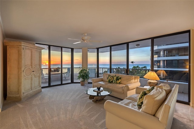 carpeted living room with ceiling fan and a water view