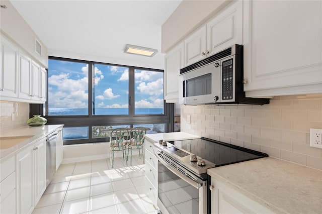 kitchen with decorative backsplash, white cabinetry, light tile patterned floors, and appliances with stainless steel finishes