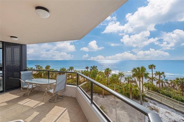 balcony with a water view and a view of the beach