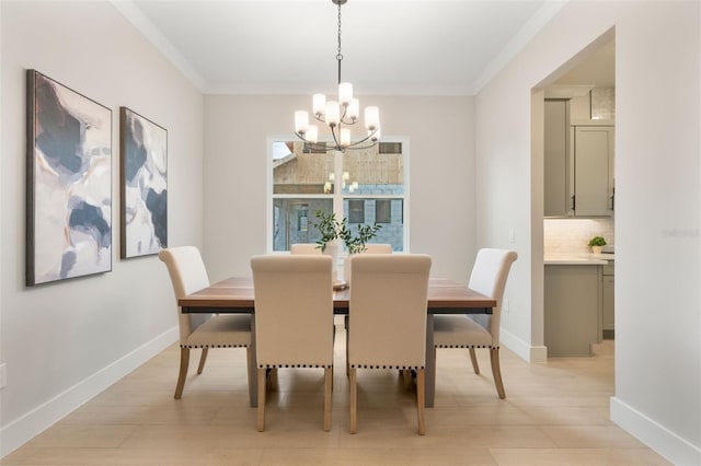 dining room featuring a chandelier, ornamental molding, light wood-style floors, and baseboards