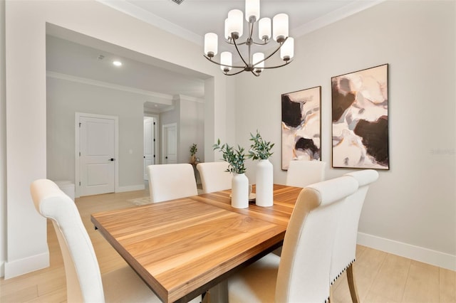 dining space featuring light wood finished floors, ornamental molding, a chandelier, and baseboards