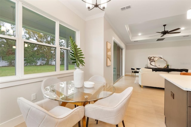 dining space with light wood finished floors, recessed lighting, a raised ceiling, visible vents, and ornamental molding