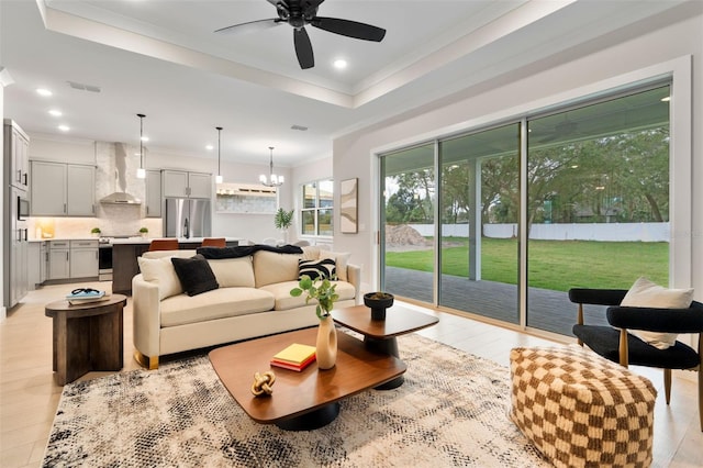 living area with a tray ceiling, recessed lighting, visible vents, and crown molding