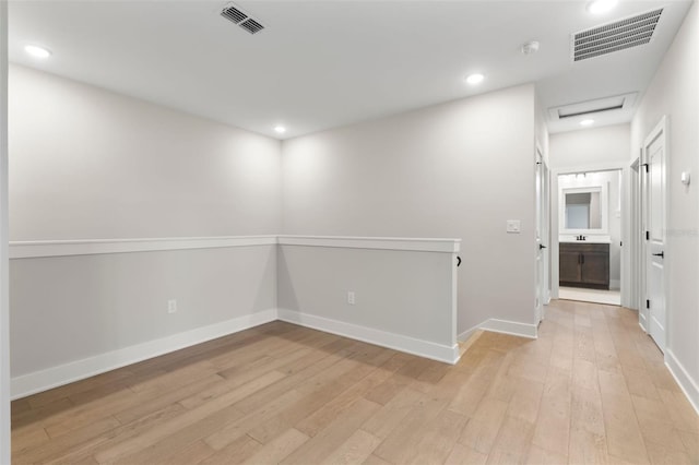 spare room featuring light wood-style flooring, visible vents, and attic access