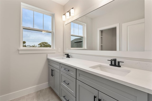 full bath featuring double vanity, a sink, and baseboards