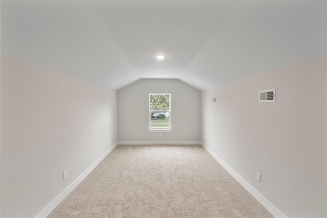 bonus room featuring lofted ceiling, light carpet, visible vents, and baseboards