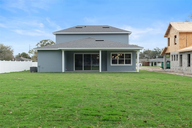 back of property featuring a yard, central AC unit, roof with shingles, and fence