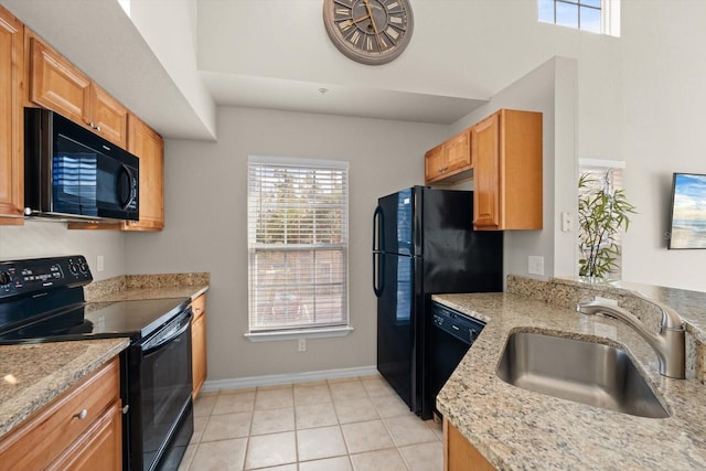 kitchen with black appliances, light stone counters, light tile patterned floors, and sink