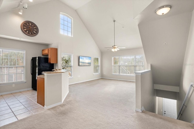 kitchen featuring kitchen peninsula, a wealth of natural light, black refrigerator, and ceiling fan