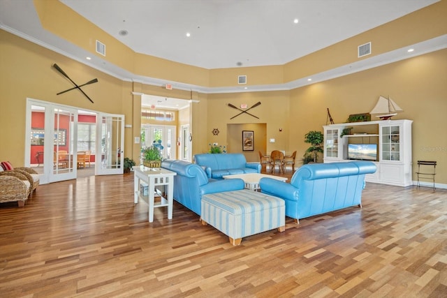 living room with light hardwood / wood-style flooring, a high ceiling, and french doors