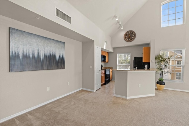 kitchen with black appliances, light colored carpet, kitchen peninsula, and high vaulted ceiling