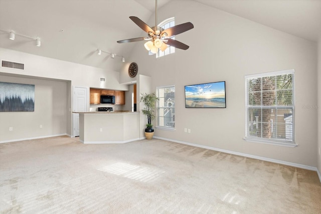 unfurnished living room with ceiling fan, high vaulted ceiling, a healthy amount of sunlight, and light carpet