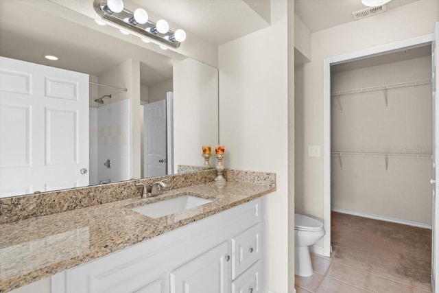 bathroom featuring tile patterned floors, vanity, toilet, and a shower