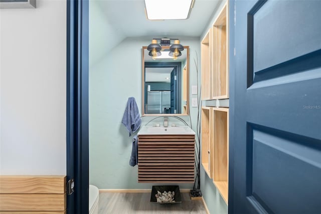 bathroom featuring vanity, wood-type flooring, and lofted ceiling