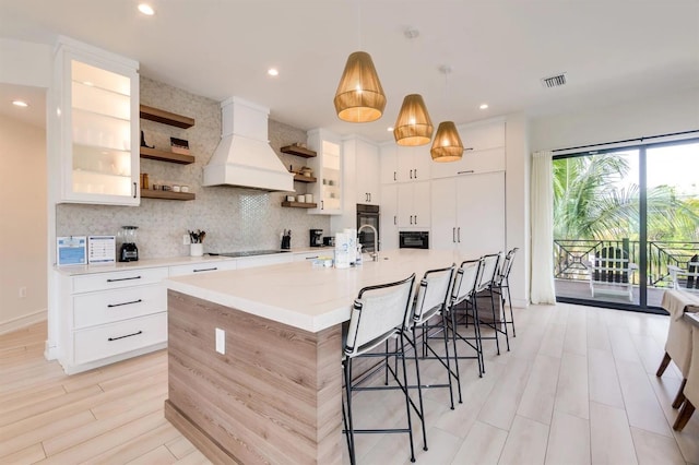 kitchen featuring white cabinetry, hanging light fixtures, a spacious island, black electric stovetop, and custom exhaust hood