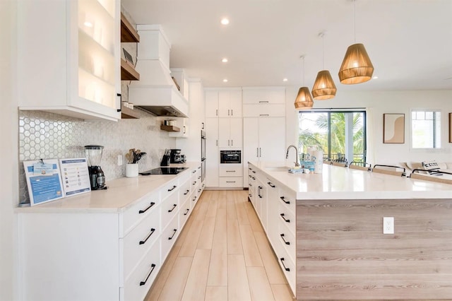 kitchen featuring a large island, white cabinetry, hanging light fixtures, tasteful backsplash, and black electric stovetop