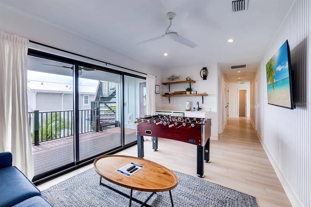 recreation room with sink, light hardwood / wood-style flooring, and ceiling fan